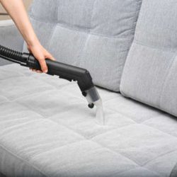 99166334-woman-cleaning-couch-with-vacuum-cleaner-at-home